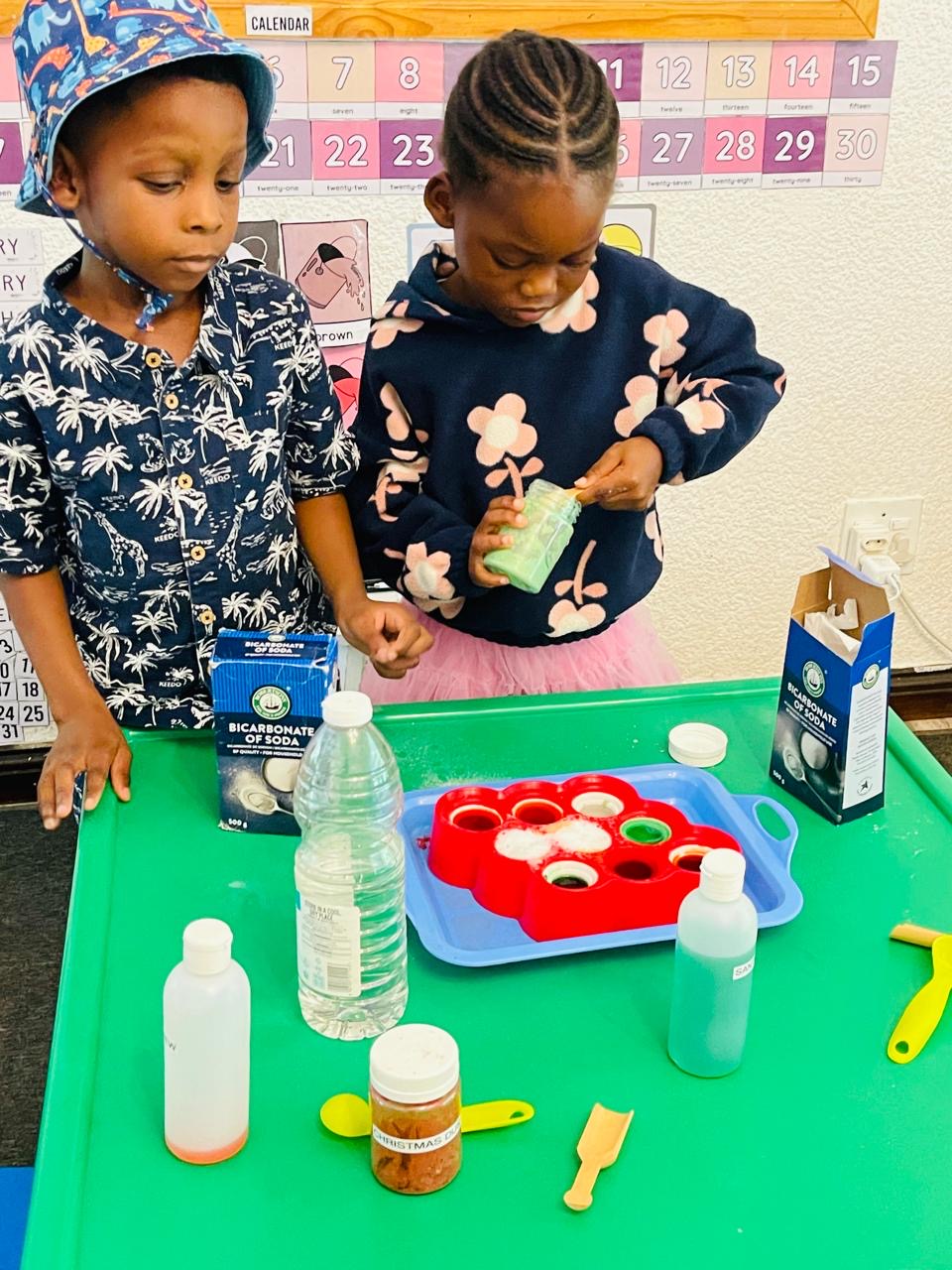 Two children mixing a bicarbonate of soda science experiment in the classroom